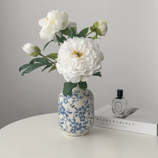 White peony artificial flower arrangement in blue ceramic vase on table