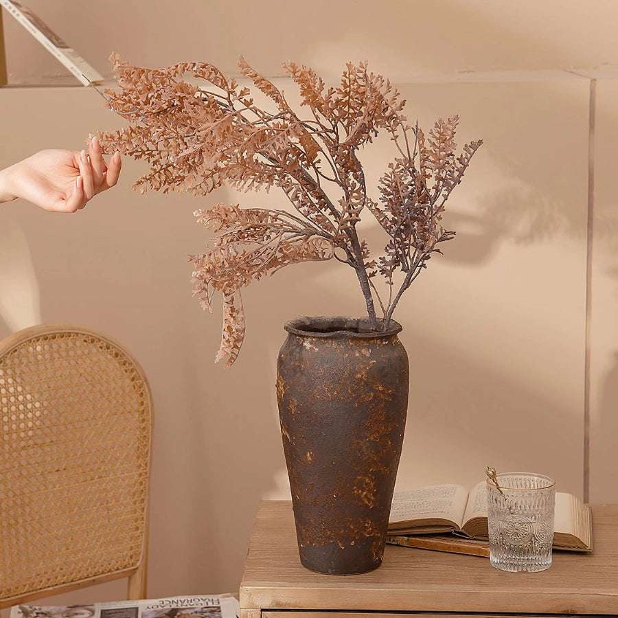 Artificial dried-look faux fern branch in a vintage vase for tablescape decoration and photography styling