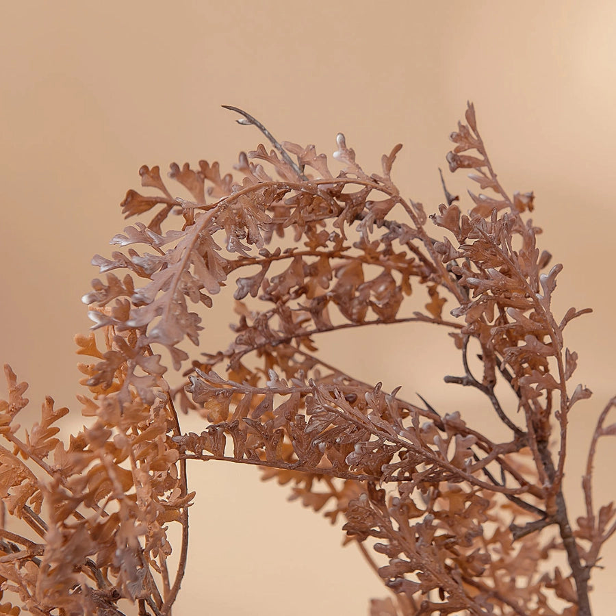 Close-up of coffee beige faux fern foliage with realistic dried-look texture for natural home decoration