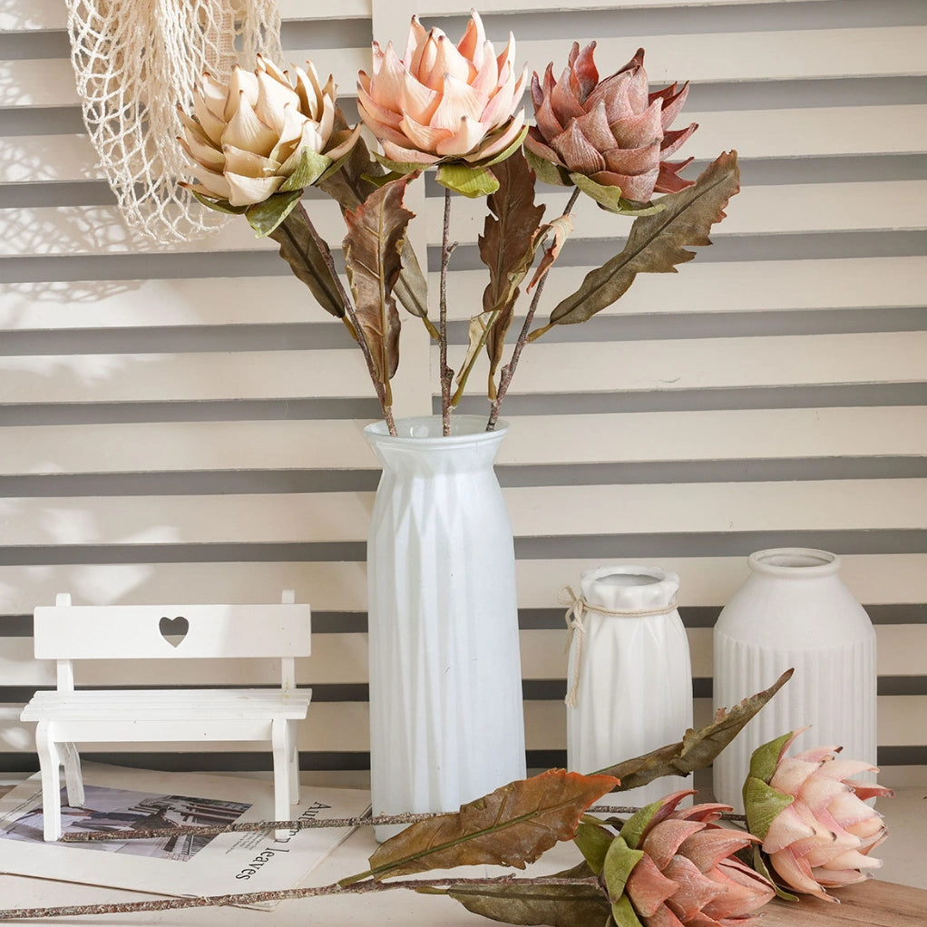 Artificial protea flower stems in white vase for aesthetic room decor and shop display