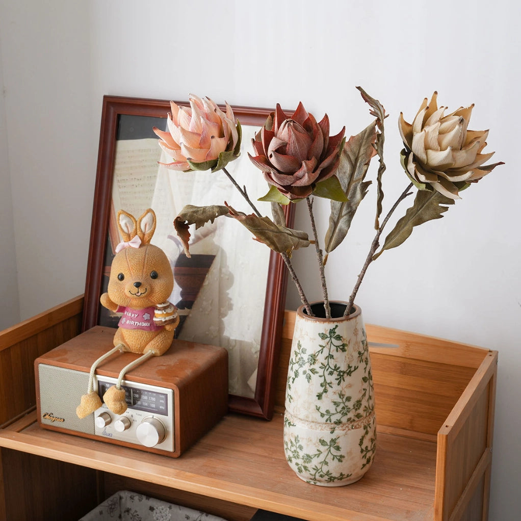 Artificial protea flower arrangement on wooden cabinet with vintage decorative accents