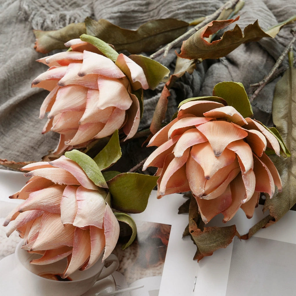 Close-up of blush pink and orange faux king protea flowers with lifelike petals