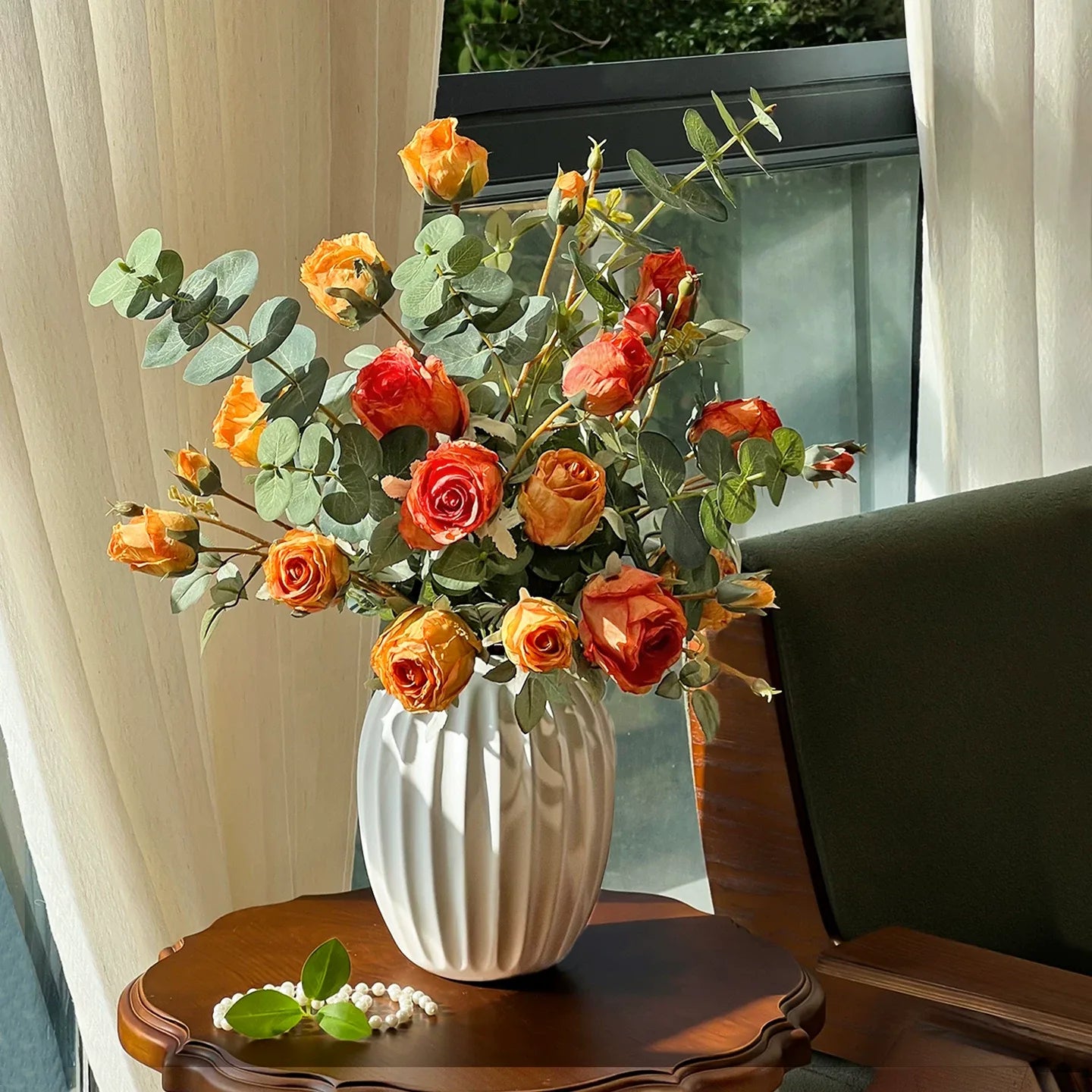 Artificial rose bouquet in vase styled on table with tea set for elegant interior decor