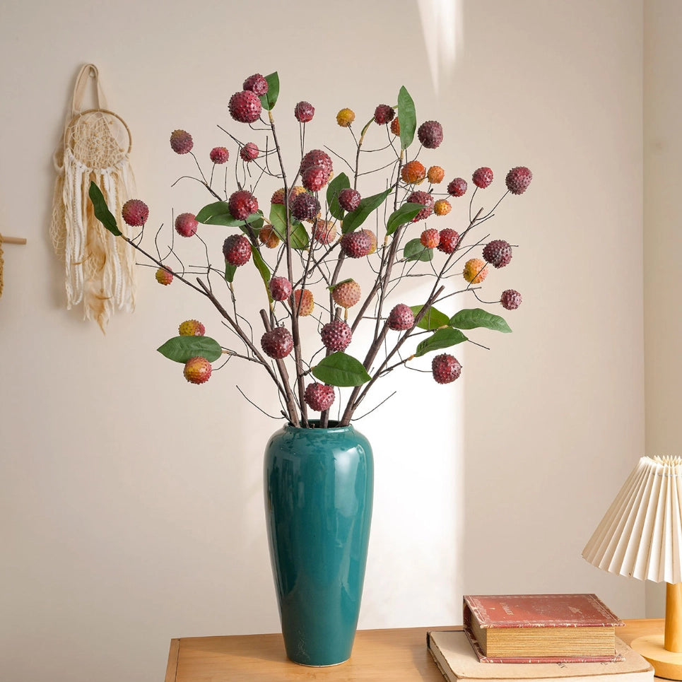 Artificial lychee branches arranged in a blue vase for Japandi living room decor