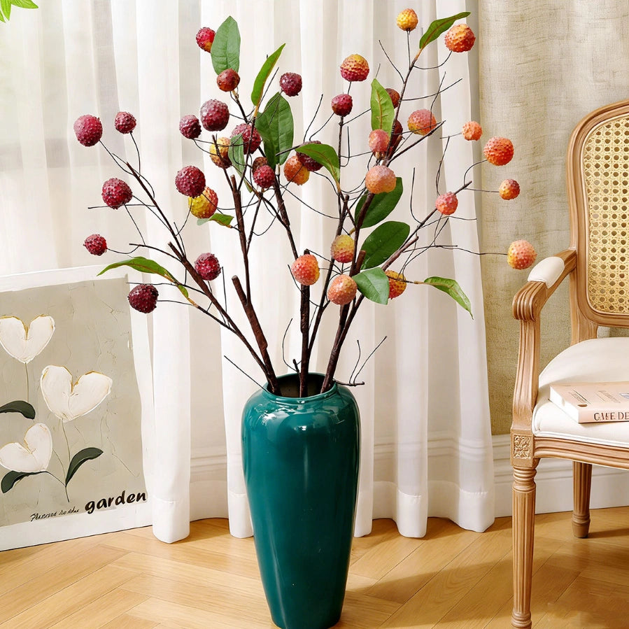 Artificial fruit branches with lychee clusters styled in a tall blue vase for home decor