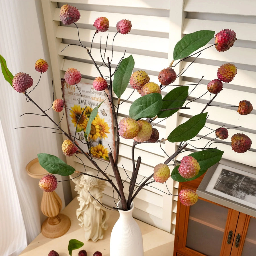 Faux lychee spray with green leaves displayed in a white vase for cozy room styling