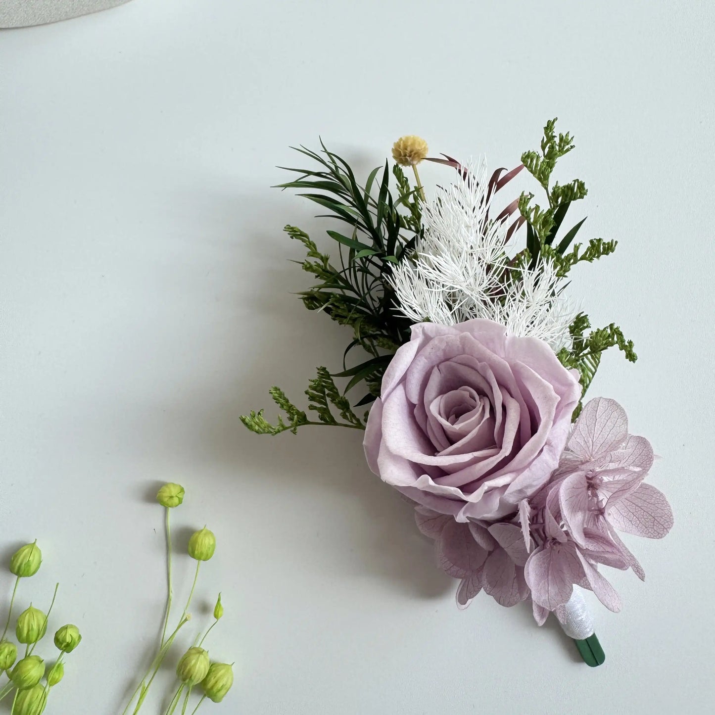 Lavender preserved rose boutonniere with greenery for groom wedding accessory