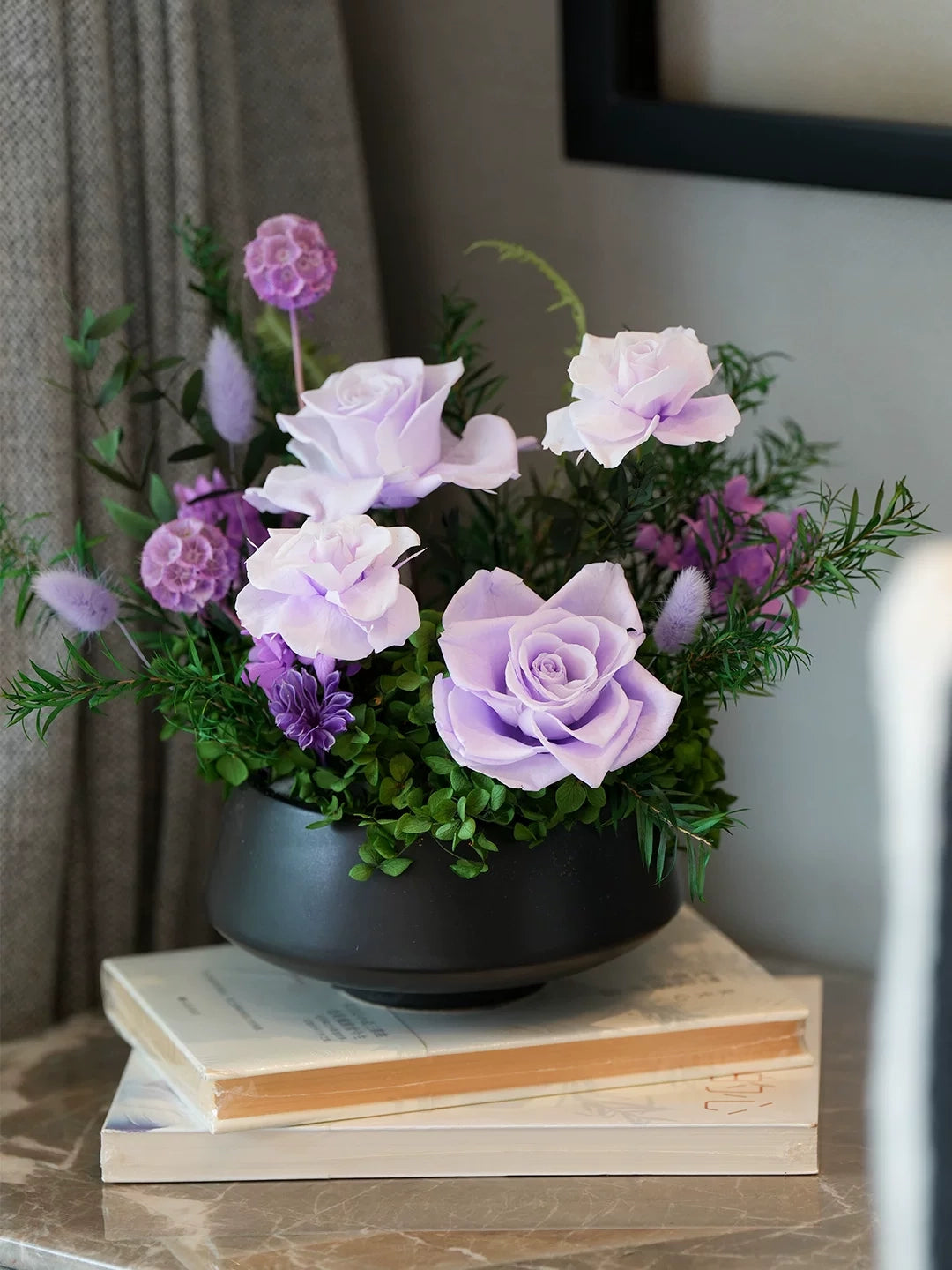 Elegant preserved rose tabletop decor placed on books, modern interior styling