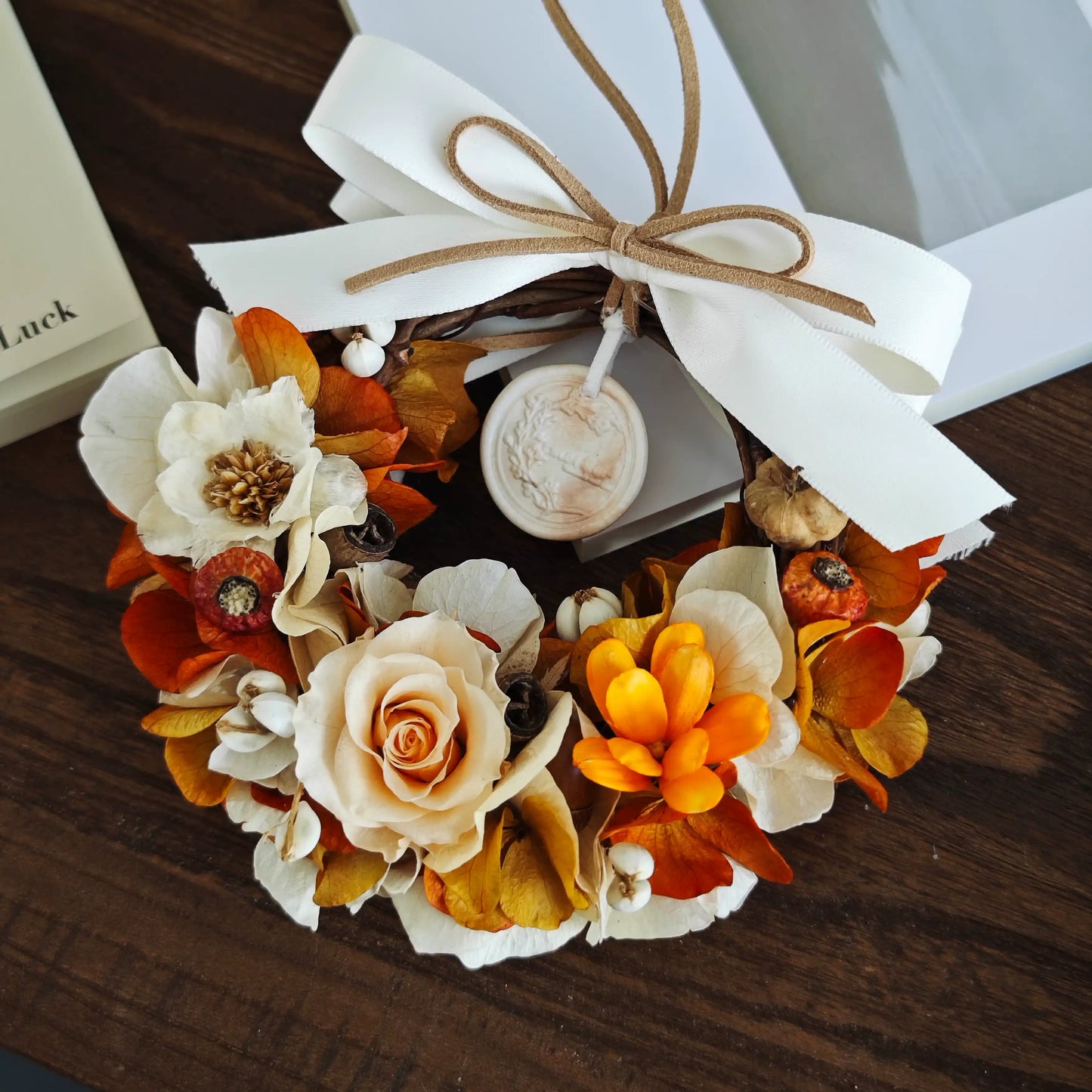 Autumn orange preserved flower wreath with white bow for seasonal home decoration
