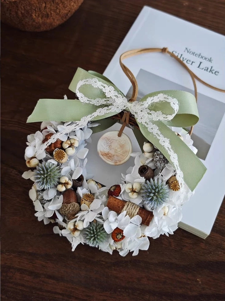 White dried flower wreath with rustic botanicals and ribbon for natural home decoration