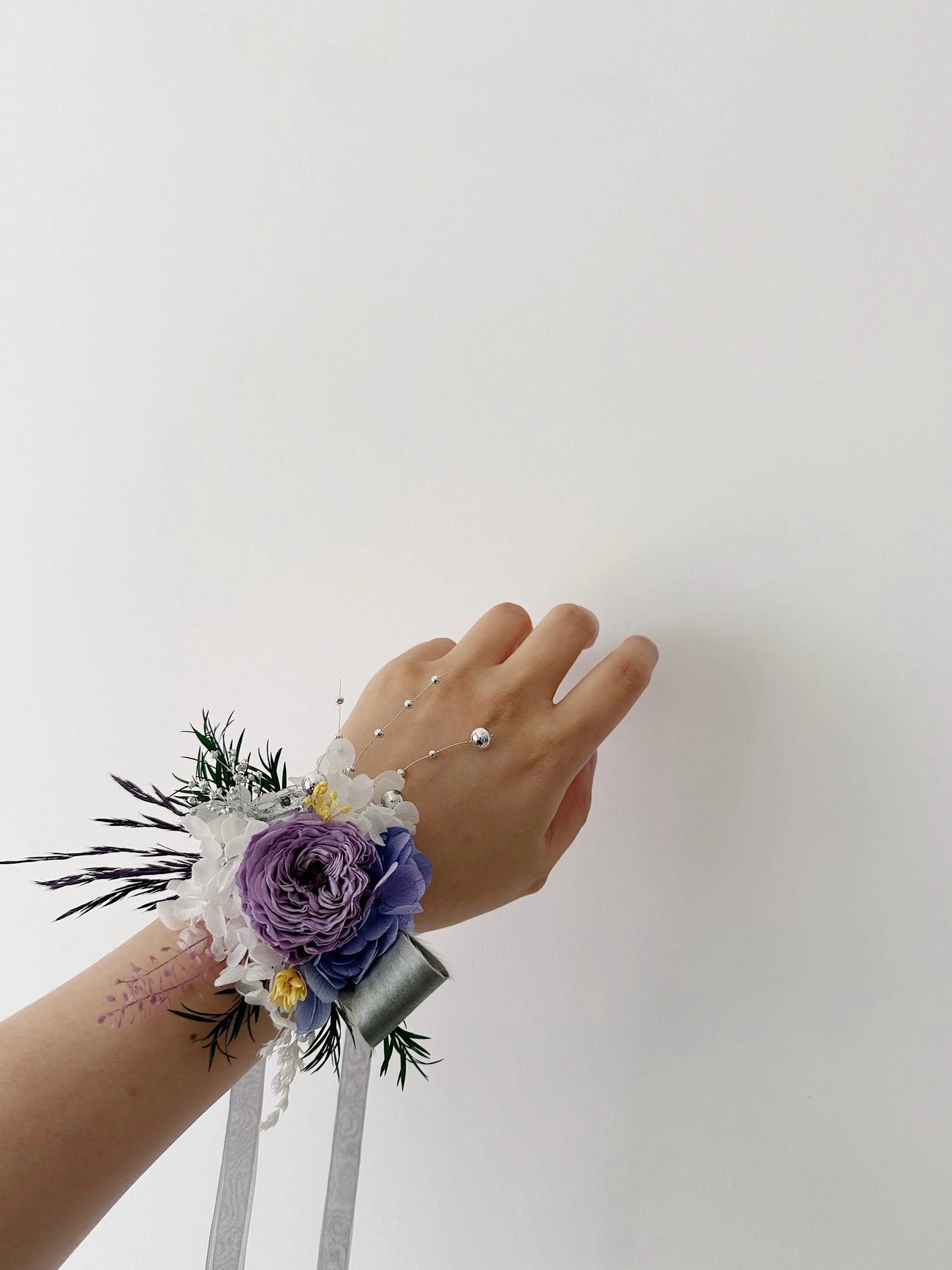 Purple preserved rose wrist corsage worn on hand for wedding styling