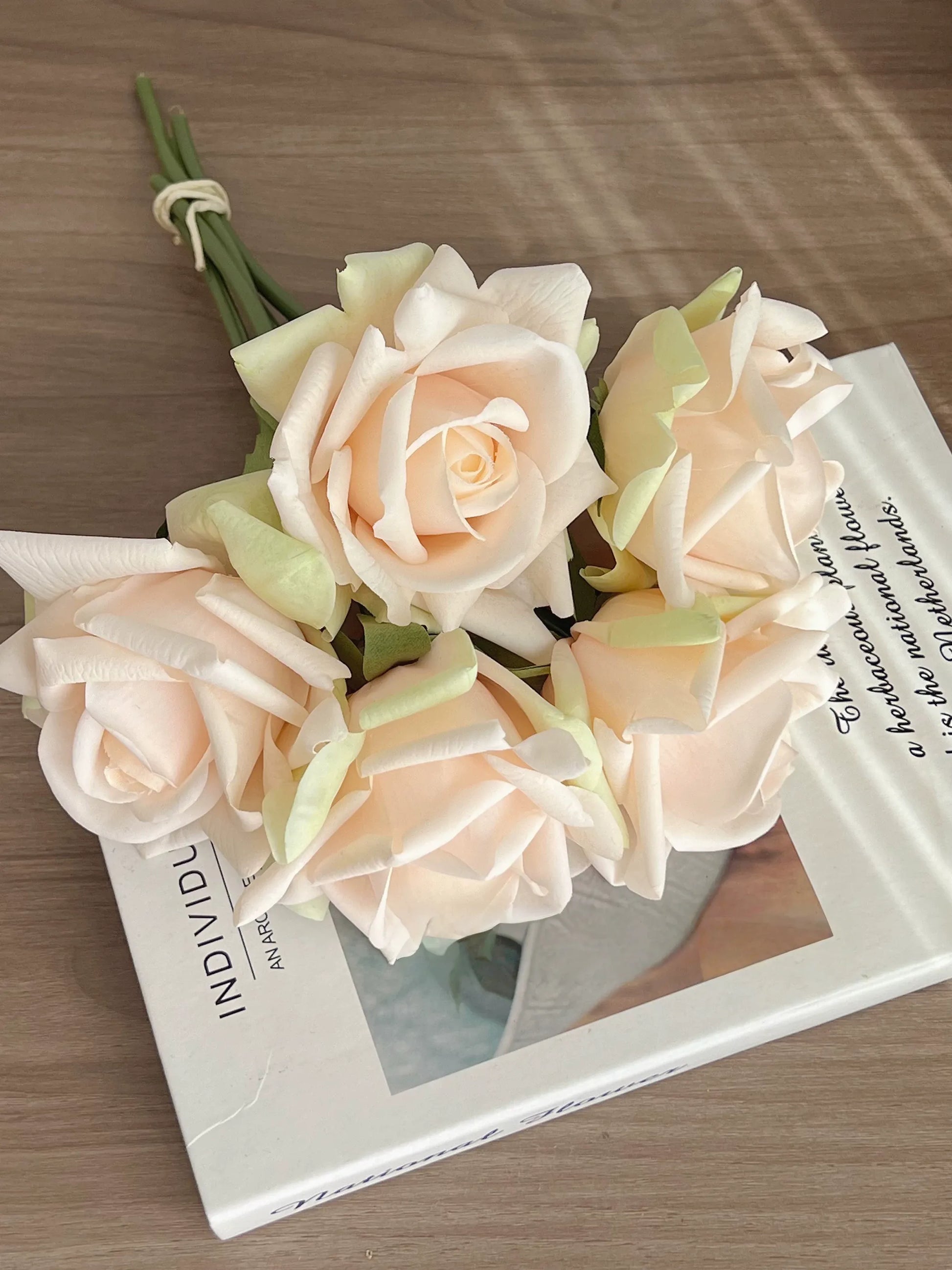 Champagne realistic artificial rose bouquet on book for elegant home decor
