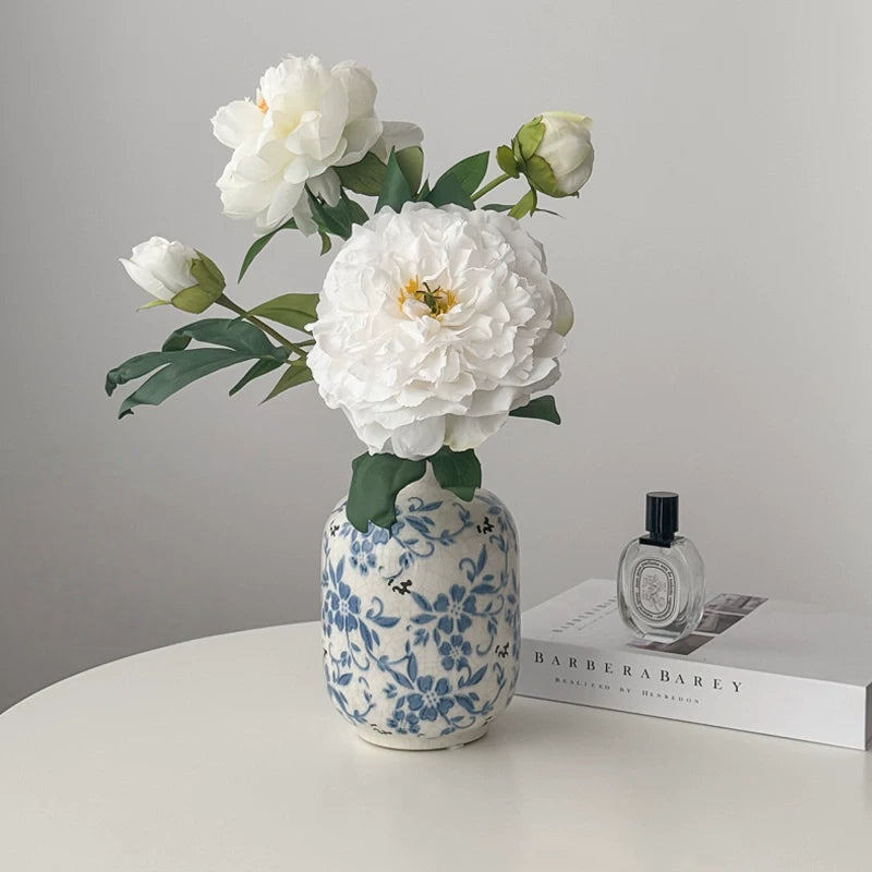 White peony artificial flower arrangement in blue ceramic vase on table